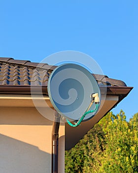 Domestic satellite tv installation under the eaves of home with octo monoblock converter. Residential TV receiver satellite dish