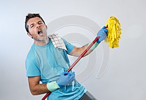 Domestic service man or happy husband cleaning home playing with mop air guitar having fun
