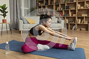 Domestic sports concept. Young asian lady in sportswear doing fitness exercises on yoga mat, working out at home