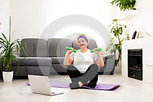 Domestic Training. Active Senior Woman Making Exersise In Front Of Laptop At Home, Free Space