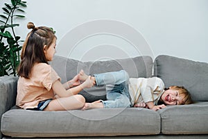 Dominant little girl tickling to tickle boy& x27;s foot, making him roll and laugh