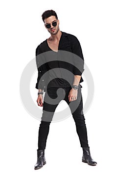 Dominant man in black clothes standing with legs parted photo