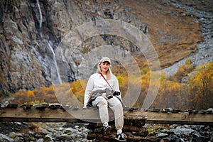 Moment of solitude, girl on the bridge by the waterfall in the mountains