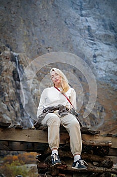 Moment of solitude, girl on the bridge by the waterfall in the mountains