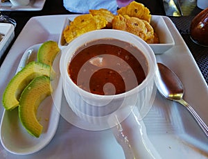 Dominican mondongo stew with fried plantains and avocado photo