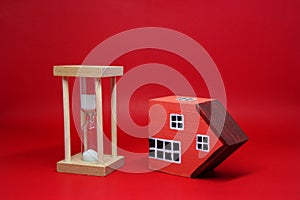 Domino effect of property home with Sand clock hourglass on red background , The impact of financial status and inflation or from