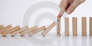 Domino effect and risk management concept. manager stops falling wooden cubes with his finger