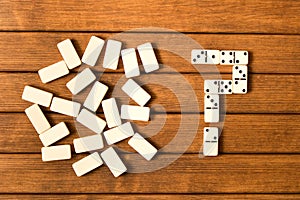 Domino on a wooden table. Question mark. The concept of the unk