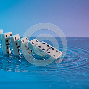 Dominoes are falling into water, creating ripples on the surface. The dominoes are photo