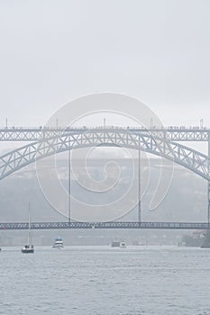 Don Luis I steel bridge wrapped in fog and full of tourists walking with umbrellas and raincoats on a very foggy and rainy day