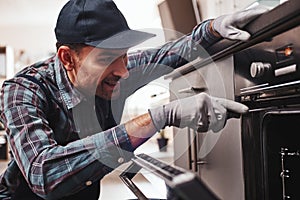 Don`t delay with repair. Close-up of repairman examining oven