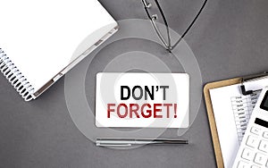 DON`T FORGET text written on the card with notebook and clipboard, grey background