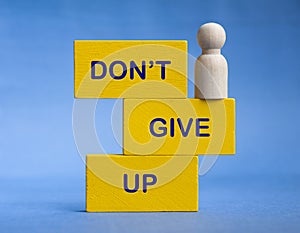 Don't give up text on wooden blocks with wooden doll standing at the edge. Motivational concept