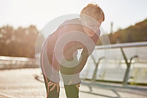 Don`t overdo it. Active mature woman in sportswear looking tired and exhausted, taking a rest after running outdoors on