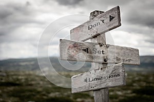 Don`t set limitations text on wooden rustic signpost outdoors in nature/mountain scenery.