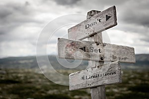 Don`t set limitations text on wooden rustic signpost outdoors in nature/mountain scenery. photo