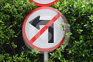 Don`t turn left sign warning on shrub background