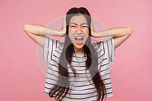 Don`t want to listen! Portrait of irritated girl with brunette hair covering ears and shouting with crazy expression