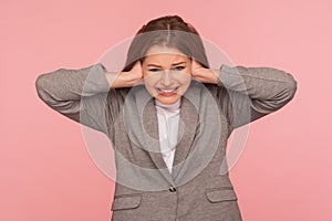 Don`t want to listen! Portrait of irritated stressed out young woman in business suit tightly covering ears