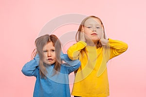 We don`t want to listen! Portrait of two naughty disobedient little girls covering ears with hands, ignoring parental advice