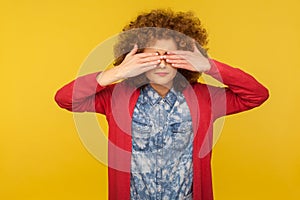 Don`t want to look. Portrait of scared woman with curly hair in casual outfit covering eyes, feeling shy