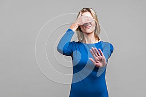 Don`t want to see! Portrait of dissatisfied woman covering eyes with hand and gesturing stop. isolated on gray background