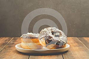 Donat. Donat in chocolate is strewed with grated almonds. Donat in a white bowl on a dark background with copy spacw