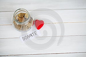 Donate conception. Jar with money on white wood background