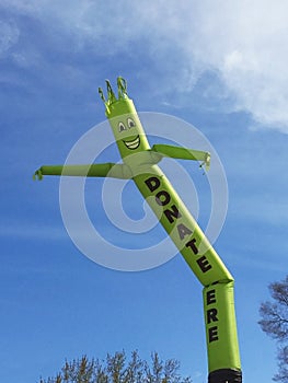 Donate Here inflatable cute cartoon character dancing against blue sky