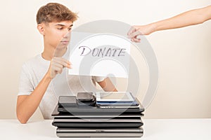 Donate old used laptop computers, phone, digital tablet to charity. Volunteers hands holding paper with text Donate