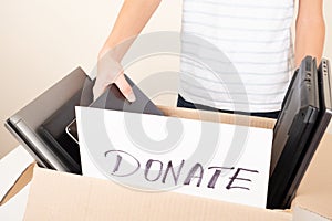 Donate technology to charity. Old used laptop computers, phone, tablet near cardboard box. Volunteer hands holding paper