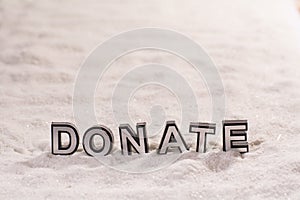 Donate word on white sand