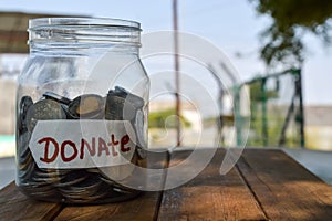 donate written label in jar and money,charity box in coins written text donate,donate written text on wooden table