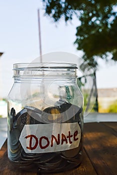 donate written text in plastic jar and money,coins in donate box or jar,money in donate written jar,charity box in coins,money in