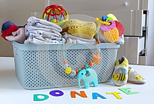 Donation box with Baby Unisex neutral clothing and donation accessories on light background