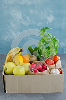 Donation box with fresh organic fruits, vegetables and herbs on a concrete background. Proper nutrition.