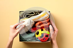 Donation box with kids clothes on a color background. Charity concept