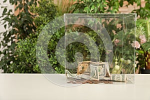 Donation box with money on table against blurred background