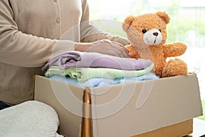 Donation box with used clothes and doll at home to support help for poor people in the world