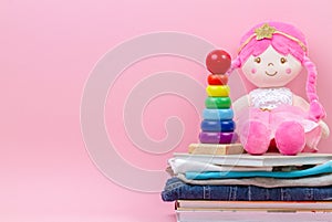 Donation, charity concept. Stuffed soft doll, baby stacking rings pyramid, kid clothes and books over pink background