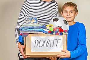 Donation concept. Donate box with clothes, books and toys in child and mother hand