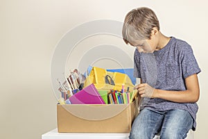 Donation concept. Kid holding donate box with books, pencils and school supplies