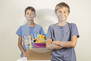 Donation concept. Kids happy to help others. Boys with donation box with books and school supplies