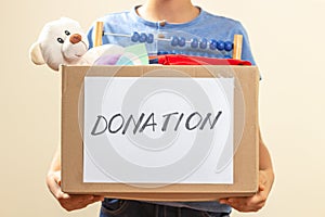 Donation concept. Volunteer hands holding donate box with clothes, books and toys for charity