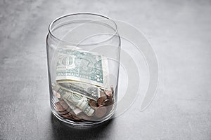 Donation jar with money on grey background.