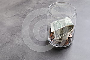 Donation jar with money on grey. Space for text