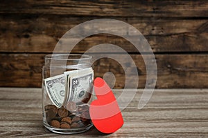 Donation jar with money and red heart on table