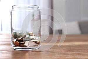 Donation jar with money on table against blurred background