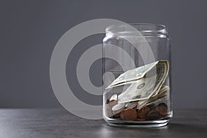 Donation jar with money on table against grey background.