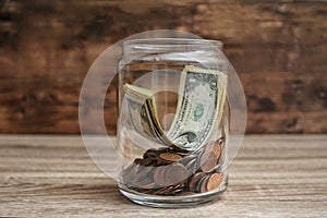 Donation jar with money on wooden